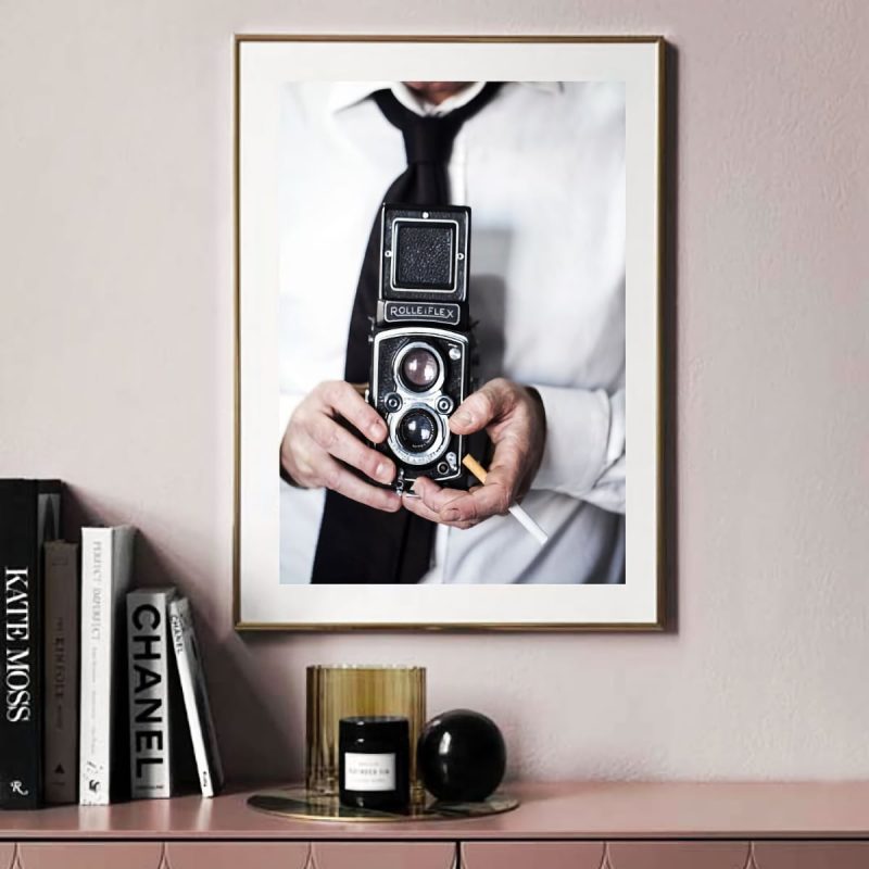 stampa uomo con Rolleiflex muru muru fiorsa square primo piano di una macchina fotografica Rolleiflex, tenuta in mano da un uomo che tiene una sigaretta tra le mani, vestito con una camicia bianca e cravatta nera
