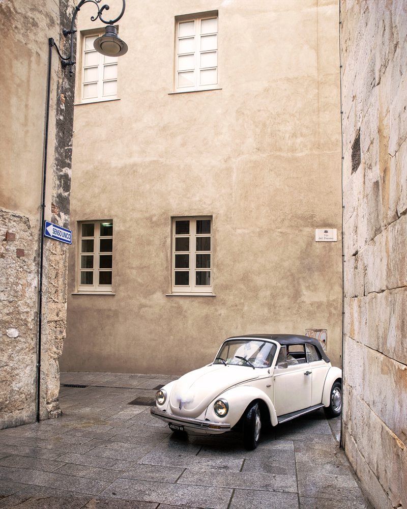 Inversione sentimentale Un Maggiolino bianco, perfettamente restaurato, sbuca da una curva con esitazione geometrica. È pomeriggio inoltrato nel quartiere Castello di Cagliari
