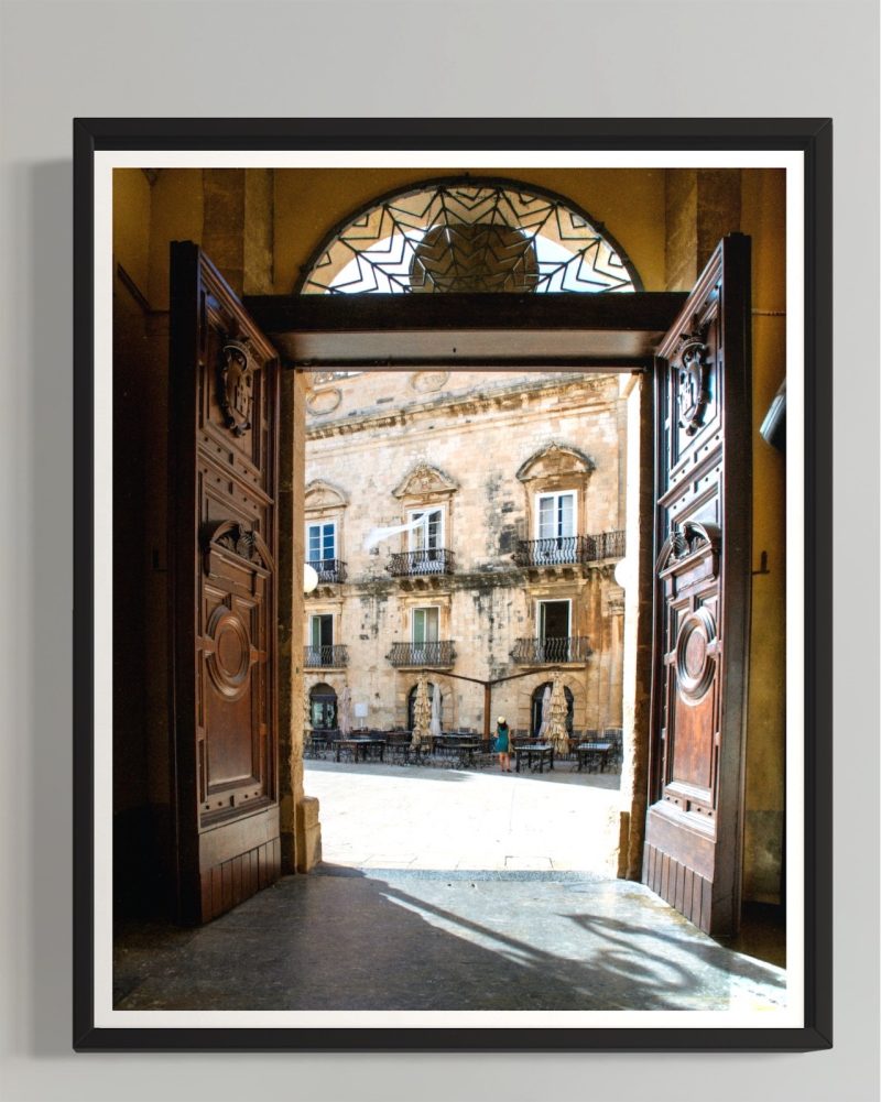 muru muru aria siciliana ambientato 02 Uno scorcio pieno di luce e fascino senza tempo: le porte aperte del Duomo di Siracusa incorniciano la piazza inondata dal sole, con i suoi palazzi barocchi all'interno di una cornice nera