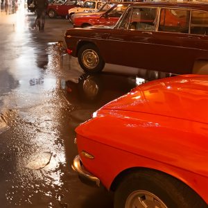 un raduno di auto d'epoca in una città con strade bagnate dalla pioggia