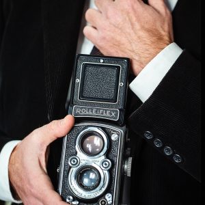 muru muru rolleiflex fuoco manuale primo piano di una macchina fotografica Rolleiflex, tenuta in mano da un uomo elegante