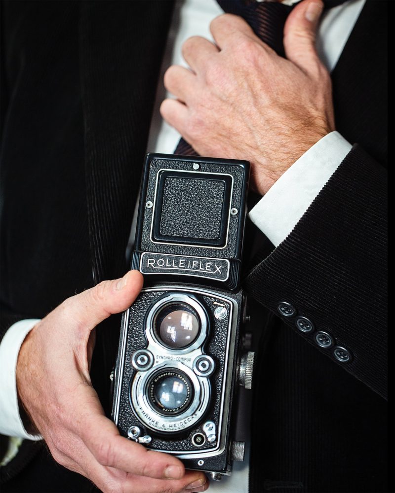 muru muru rolleiflex fuoco manuale primo piano di una macchina fotografica Rolleiflex, tenuta in mano da un uomo elegante